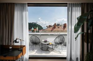 فندق سيتي ليوبليانا في ليوبليانا: غرفة مع شرفة مع طاولة وكراسي