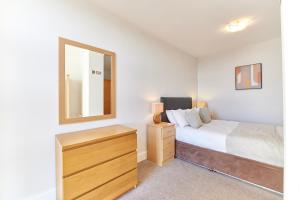 a bedroom with a bed and a dresser and a mirror at Low Friars - Properties Unique in Newcastle upon Tyne
