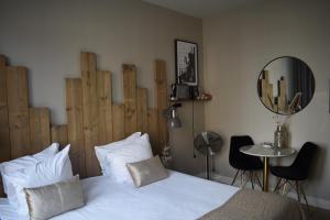 a bedroom with a white bed with a wooden headboard at Boutique Nouveau Van Ham in Breda