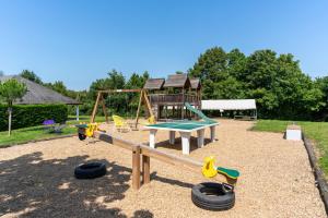 a playground with a slide and swings and tires at Residence Les Villas CROMA in La Roche-Posay