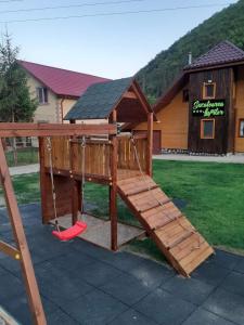 a wooden playground with a swing and a roof at SEZATOAREA LUPILOR in Lepşa
