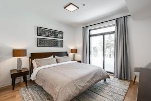 a bedroom with a bed and a large window at Tremblant-Les-Eaux Le Contemporain by Gestion ELITE in Mont-Tremblant