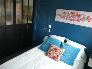 a bed with blue walls and two pillows on it at Studio Cosy proche Grand-Champ Home Sweet Home in Plumergat