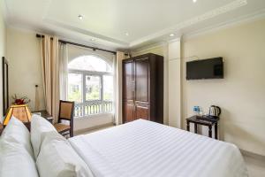 Un dormitorio con una gran cama blanca y una ventana en La Bonita Hotel and Apartments en Ho Chi Minh