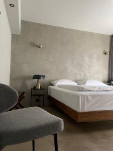 a bedroom with a bed and a lamp and a chair at Hotel Mons am Goetheplatz in Munich