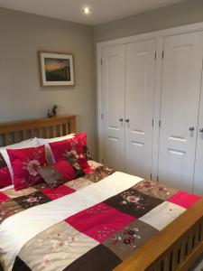 a bedroom with a large bed with red pillows at Seaside Stay in Rustington