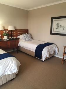 1 dormitorio con 2 camas y escritorio con lámpara en Bay Haven, en Gansbaai