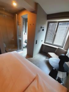 a bedroom with a bed and a chair and a window at Hotel Mons am Goetheplatz in Munich