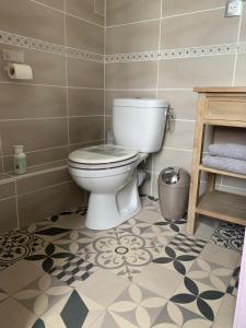 a bathroom with a toilet and a tile floor at Chambre d'hôtes - La Pinstrie 