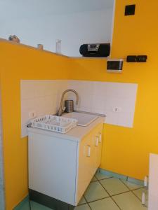 una cucina con lavandino e parete gialla di Palmarosa Apartments superior a Ercolano