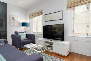 A Stunning Three Bedroom Home in Mayfair في لندن: غرفة معيشة مع أريكة وتلفزيون بشاشة مسطحة