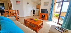 a living room with a blue couch and a table at Holiday flat BLUE OCEAN, beachfront, sea view, 1 bedroom, livingroom, fast internet in Costa Calma