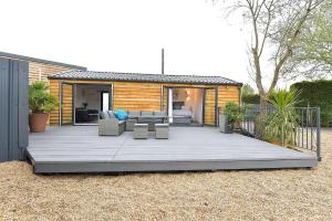 a large wooden deck with furniture and a house at Cheerful 1BD Cottage with Parking Nr Guildford in Guildford