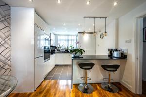 a kitchen with white walls and a counter with stools at Stunning 1BD Flat close to Manchester City Centre in Manchester