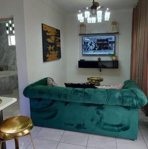 un sofá verde en una sala de estar con TV en Elegant Airbnb en Pretoria