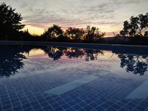 a swimming pool with a sunset in the background at Vivenda das Eiras in Vale de Porco