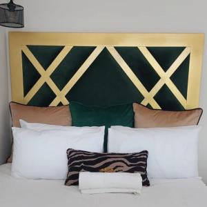 1 cama con almohadas blancas y cabecero verde y dorado en Elegant Airbnb en Pretoria