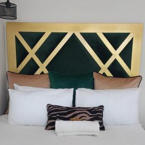 a bed with white pillows and a green and gold headboard at Elegant Airbnb in Pretoria