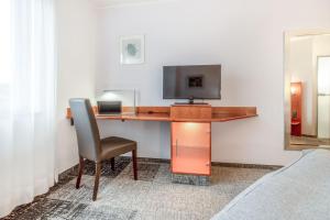 einen Schreibtisch mit einem TV und einem Stuhl in einem Zimmer in der Unterkunft Select Hotel Oberhausen in Oberhausen