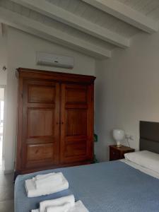 1 dormitorio con 1 cama y armario de madera con toallas en Bilocale in residence vista lago con piscina, en Polpenazze del Garda