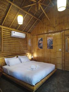 - une chambre avec un grand lit dans un mur en bois dans l'établissement สวนเกษตรรักษ์ไผ่ Bamboo Conservation Farm, à Surin