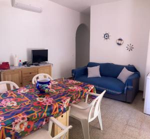ein Wohnzimmer mit einem Tisch und einem blauen Sofa in der Unterkunft Like Home Calamazzo di Sciacca in Scopello