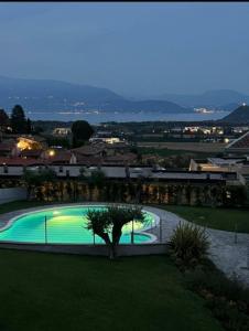 a swimming pool with a tree next to a building at Bilocale in residence vista lago con piscina in Polpenazze del Garda
