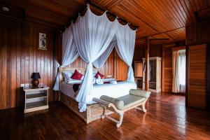 a bedroom with a canopy bed with red pillows at Munduk Menir Villas in Munduk
