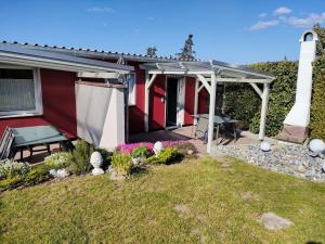 ein rotes Haus mit Markise und Terrasse in der Unterkunft Ferienhaus "Sommerbrise" in Gager