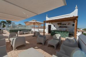 eine Terrasse mit Stühlen, Tischen und einem Sonnenschirm in der Unterkunft Hotel La Malvasía in El Rocío