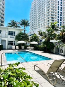 ein Pool mit Stühlen und Sonnenschirmen sowie ein Gebäude in der Unterkunft Aqua Hotel in Fort Lauderdale