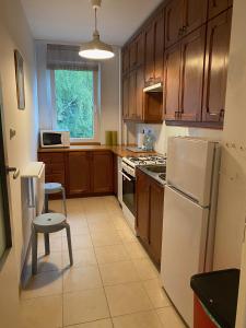 a kitchen with wooden cabinets and a white refrigerator at Burgaska 5 XL Size in Warsaw