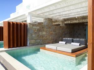 a swimming pool with a bench and a tub in front of it at Bill & Coo Suites and Lounge -The Leading Hotels of the World in Mikonos