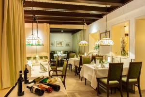 a dining room with white tables and chairs and chandeliers at Lampes Posthotel in Grünenplan