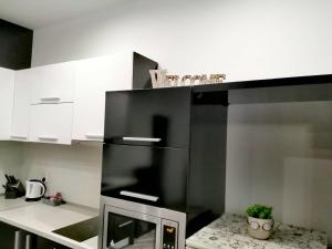 a kitchen with a black refrigerator and white cabinets at Апартамент ЗАПАД in Kazanlŭk