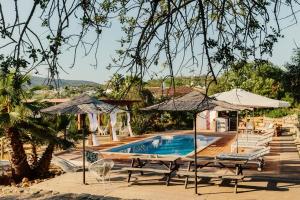a swimming pool with two umbrellas and a house at Quinta Bohemia in Moncarapacho