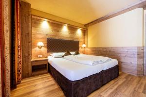 a bedroom with a large bed in a room with wooden walls at Zimmerhofer A3 Panorma in Cadipietra