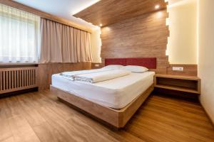 a bedroom with a bed with a wooden wall at Zimmerhofer C Dolomiti in Cadipietra