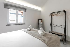 Habitación blanca con cama y ventana en Beach Alley Apartment, en Nazaré