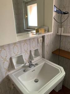 uma casa de banho com um lavatório branco e um espelho. em Amica em Salsomaggiore Terme