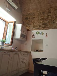 uma cozinha com armários brancos, uma mesa e uma janela em Matalena em Pomarico