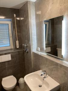 ein Badezimmer mit einem Waschbecken, einem WC und einem Spiegel in der Unterkunft Ferienwohnung Winkler in Augsburg