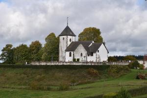 a white church on top of a green field at Ferienwohnung EifelMittendrin in Waxweiler