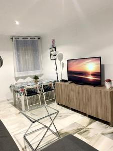 - un salon avec une télévision à écran plat dans un centre de divertissement en bois dans l'établissement NICE APART LOS BOLICHES BEACH WIFI PARKING, à Fuengirola