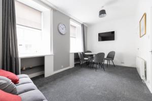 a living room with a couch and a table with chairs at Lovely City Centre 1 bedroom flat. in Perth