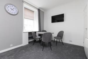 uma sala de espera com uma mesa e cadeiras e um relógio em Lovely City Centre 1 bedroom flat. em Perth