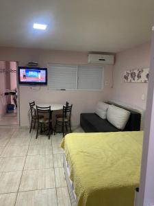 Una habitación con una cama, una mesa y un televisor. en Sobrado 03 na Praia de Bombas, en Bombinhas