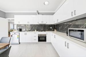 a white kitchen with white cabinets and appliances at New 2 Bedroom House 500m to Mall with Free Parking in Bankstown