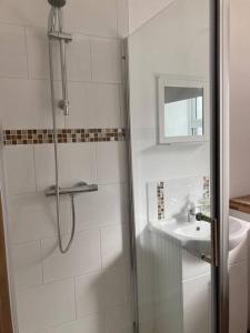 a white bathroom with a shower and a sink at Marni’s Cottage - Rural location & fell views in Frizington
