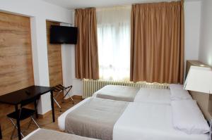 a hotel room with two beds and a desk and a window at Hotel Terranova in Pas de la Casa